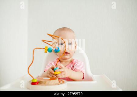 Kleines Mädchen spielt mit einem pädagogischen Labyrinth Spielzeug. Entwicklung von Feinmotorik und logischem Denken Stockfoto