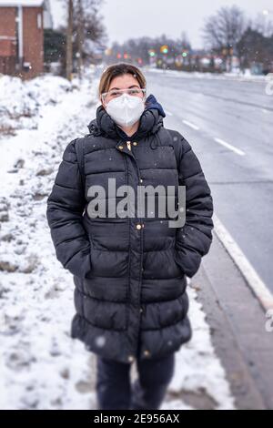 Covid-19 oder Coronavirus, eine Frau mit einer schützenden Gesichtsmaske im Winter, Kanada, 2021 Stockfoto