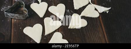 Herzschablone für Cookies. Herzförmige Löcher. Roher Teig in Form eines Herzens. Stockfoto