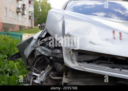 Nahaufnahme auf der rechten Vorderseite des silbernen Autos, das bei einem Verkehrsunfall physisch beschädigt wurde, Nahaufnahme mit verschwommenem Hintergrund. Stockfoto