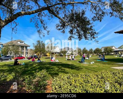 Orlando, FL USA - 30. Januar 2021: Menschen jeden Alters machen Yoga in einem Nachbarschaftspark an einem sonnigen Morgen. Stockfoto