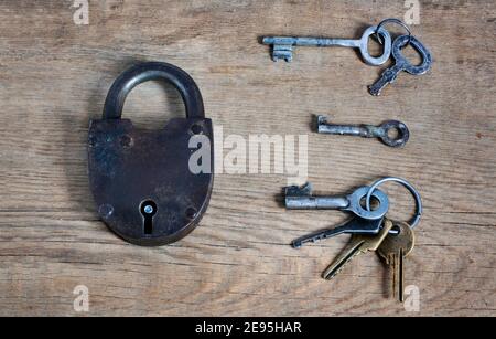 Altmodisches rostiges Schloss mit Schlüsseln auf Holzoberfläche Stockfoto