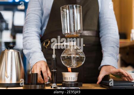 Kaffeebrühe mit Syphon Gerät. Nahaufnahme Siphon heizt durch Feuer. Brauen Foto auf dem Feuer. Alternative Methode der Kaffeeherstellung. Stockfoto