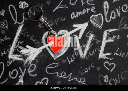 Tafel mit Herz und Pfeil und das Wort Liebe in mehreren Sprachen der Welt, geschrieben in Kreide. Stockfoto