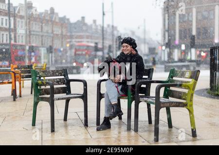 Ein junges Mädchen sitzt bei starkem Schnee mit einem Hund auf dem Schoß, Windrush Square, Brixton, London, 24. Januar 2021 Stockfoto