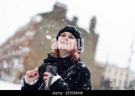 Ein junges Mädchen schaut in den Himmel und lächelt bei starkem Schnee, Winrush Square, Brixton, London, 24. Januar 2021 Stockfoto