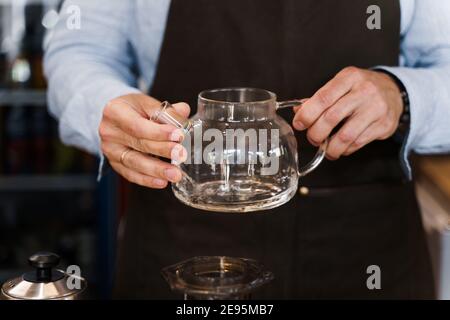 Der Barista dreht sich in den Händen und schaut mit dem Kaffee auf den Topf, bevor er Aeropress macht. Kaffeebrauprozess. Skandinavische Kaffeebrühmethode Stockfoto