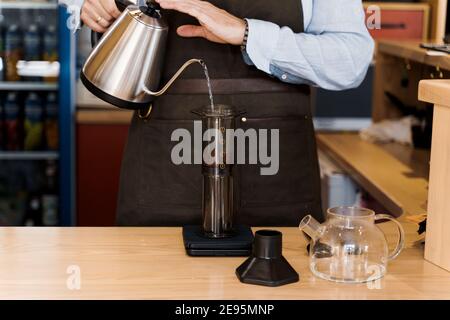 AeroPress Kaffee alternative Herstellung von Barista im Café. Skandinavische Kaffeebrühmethode. Barista gießt Wasser in die Luft mit Kaffee unter Verwendung von kat Stockfoto