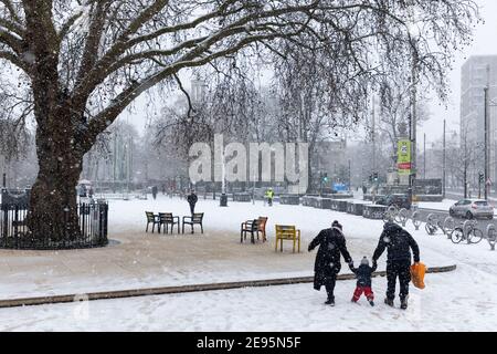 Eltern halten die Hände ihres Kleinkindes bei starkem Schnee, Windrush Square, Brixton, London, 24. Januar 2021 Stockfoto