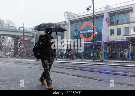 Ein Mann mit Sonnenschirm läuft bei starkem Schnee entlang der Brixton Road, Brixton, London, 24. Januar 2021 Stockfoto