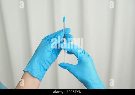 Hände in blauen Nitrilhandschuhen, die die Spritze mit Impfstoff halten. Impfkonzept für Coronaviren. Stockfoto