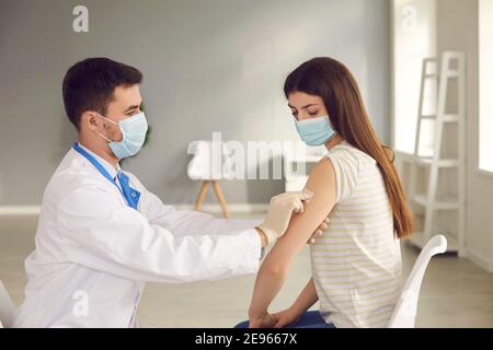 Der Arzt legt den Pflaster auf den Arm des Patienten, nachdem er ihr eine saisonale Grippe eingespritzt hat. Stockfoto