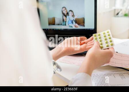 Nahaufnahme EINER Frau Videokonferenzen mit Ärztin auf Laptop.Online Kinderärzteberatung. Mama und Baby in ihren Armen sprechen via Video.Offer Stockfoto