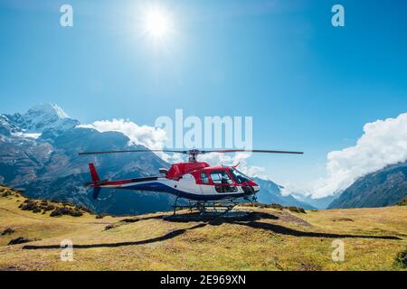 Zivilhubschrauber landete in hohen Höhen Himalaya Berge. Thamserku 6608m Berg im Hintergrund. Namche Bazaar, Nepal. Sicherheitslufttransport Stockfoto