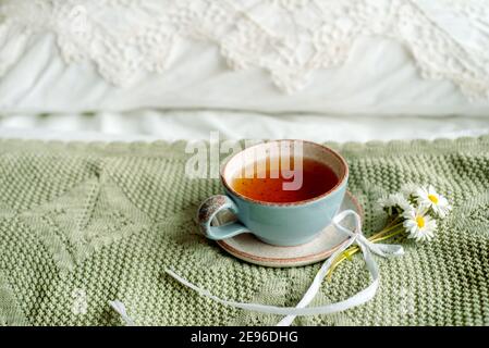 Eine Tasse Kaffee und ein offenes Buch auf weißem, offenem Bett. Frühstück am Morgen. Strahlend gemütlicher Tag Stockfoto