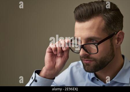 Konzentrierte Person, die ihre Brille abnimmt, während sie in die schaut Distanz und Denken Stockfoto
