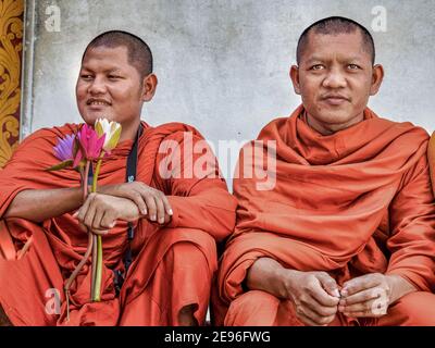 DAMBULLA, SRI LANKA - 12. März 2019: Zwei lächelnde südasiatische buddhistische Mönche mit Blumen auf Treppen. Stockfoto