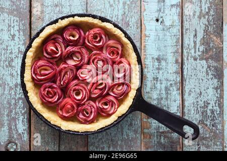 Leckere gesunde Torte. Apfelrose Tarte in Gusseisen Pfanne auf alten blauen Hintergrund Copyspace Stockfoto
