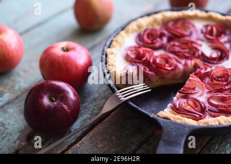 Hausgemachter leckerer Kuchen. Apfeltarte in gusseiserner Pfanne mit roten Äpfeln auf schäbigen blauen Hintergrund Nahaufnahme Stockfoto