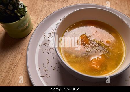 Gemüsesuppe oder Brühe mit Kürbis und Kichererbsen in einer Schüssel. Feine Streukräuter. Massivholz Hintergrund. Gesundes, veganes und diätetische Lebensmittel Stockfoto