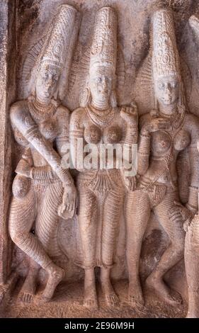 Aihole, Karnataka, Indien - 7. November 2013: Ravanaphadi Cave Temple. Nahaufnahme einer braun-beigen Steinskulptur von 3 himmlischen Mädchen. Stockfoto