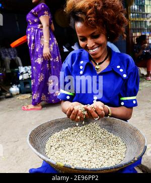 Eine Tigray-Frau, die in Axum, Äthiopien, Abfall aus dem Stapel frischer Kaffeebohnen aussortiert. Stockfoto