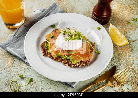 Toast mit Avocado-Püree, Lachs, pochiertem Ei und Microgreens Stockfoto