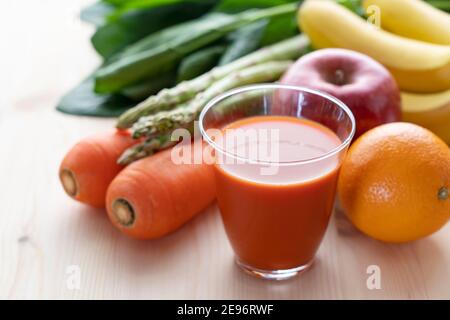 Viele verschiedene Arten von Gemüse und Obst auf einem hölzernen Hintergrund, und ein Glas Gemüsesaft Stockfoto
