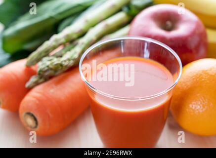 Viele verschiedene Arten von Gemüse und Obst auf einem hölzernen Hintergrund, und ein Glas Gemüsesaft Stockfoto