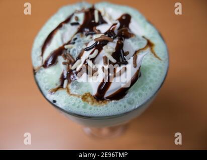 Milchshake mit Schokoladenstückchen und Sirup auf einem Tisch Stockfoto