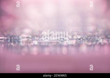 Wassertropfen funkelnd und funkelnd auf rosa Oberfläche, abstrakter Hintergrund Stockfoto