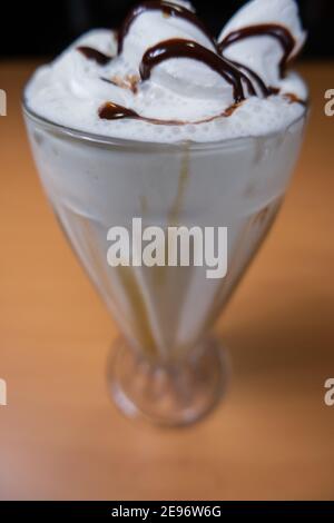 Vanillemilchshake mit Schokoladensirup auf einem Tisch Stockfoto