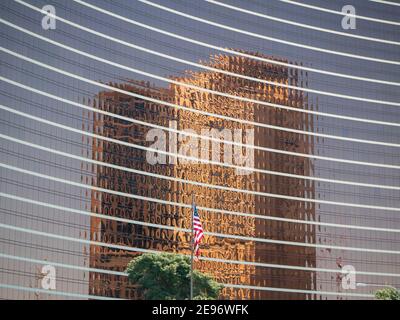 Kupferfarbenes Hochhaus, das auf einem anderen Hochhaus mit amerikanischer Flagge reflektiert wird Stockfoto