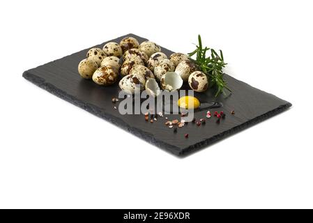 Wachtelei gebrochen auf dem schwarzen Stein mit einem anderen Eier und Rosmarin, Pfeffer Stockfoto