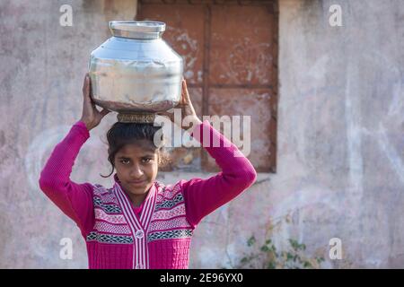 TIKAMGARH, MADHYA PRADESH, INDIEN - 23. JANUAR 2021: Ein nicht identifiziertes indisches Dorfmädchen trägt Wasser auf ihren Köpfen in traditionellen Töpfen aus Brunnen. Stockfoto