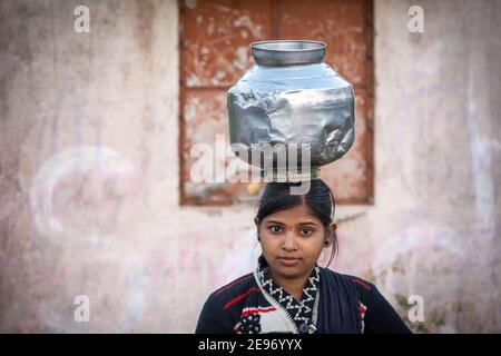 TIKAMGARH, MADHYA PRADESH, INDIEN - 23. JANUAR 2021: Ein nicht identifiziertes indisches Dorfmädchen trägt Wasser auf ihren Köpfen in traditionellen Töpfen aus Brunnen. Stockfoto