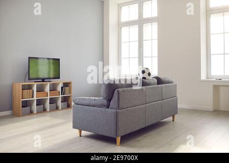 Modernes Wohnzimmer mit gemütlicher Couch und TV Set mit einem Fußballspiel auf Stockfoto