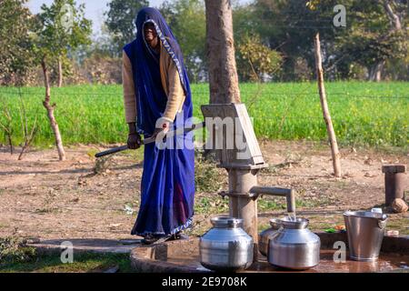 TIKAMGARH, MADHYA PRADESH, INDIEN - 23. JANUAR 2021: Unbekannte Inderin, die Handpumpe für Trinkwasser verwendet. Stockfoto