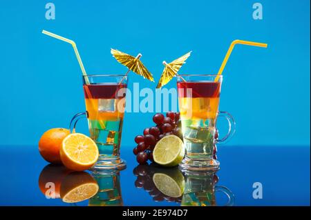 Zwei helle Sommercocktails in einem Glas mit Obst Ein blauer Hintergrund Stockfoto