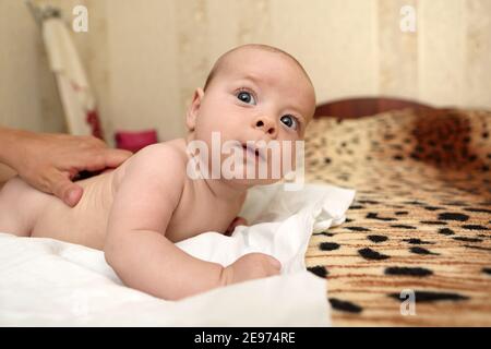 Mutter massiert den Rücken des Babys auf das Bett Stockfoto