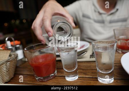 Person Gießen Wodka aus einer Karaffe in der Kneipe Stockfoto