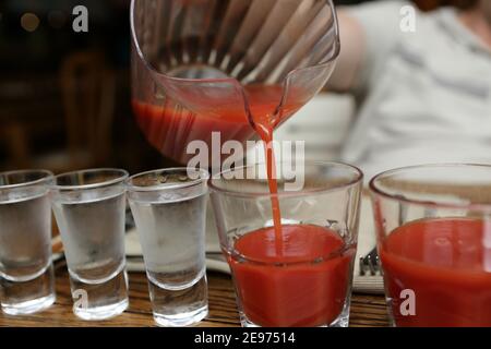 Person, die Tomatensaft in die Kneipe gießt Stockfoto