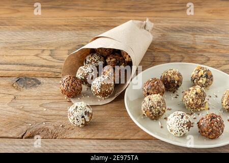 Energiebisse mit Nüssen, Samen, Trockenfrüchten und Honig - vegane oder vegetarische rohe Bio-Snack-Müslibisse auf Holzhintergrund. Stockfoto