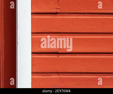 Eine alte rote Außenwand aus Holz mit einem weißen Rahmenelement links, ein nützliches Bild für den Kopierraum. Stockfoto