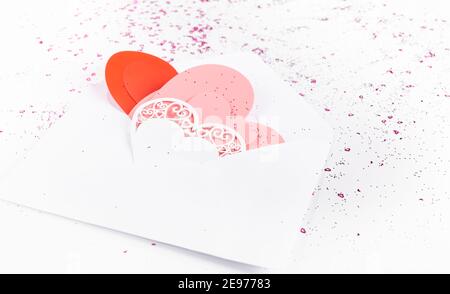 Liebesbrief, Umschlag mit Papier Handwerk Herzen auf Hintergrund mit Konfetti Stockfoto