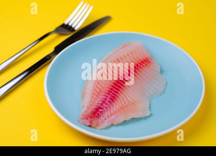 Farbige Platte mit frischem Fischfilet isoliert auf gelb. Stockfoto