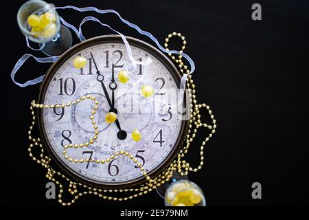 Ein Zifferblatt vor Mitternacht am Silvesterabend in Spanien mit zwei Sektflöten mit zwölf Trauben Stockfoto