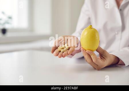 Nahaufnahme der Hände des Arztes mit Zitrone und Vitamin C oder Nahrungsergänzungsmittel Pillen Stockfoto