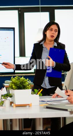 Weibliche Projektmanagerin, die ein Finanzmeeting mit statistischen Grafiken und Diagrammen auf einem interaktiven Whiteboard-Touchscreen-Gerät abhält. Executive Director arbeitet im Broadroom der Kreativagentur. Stockfoto