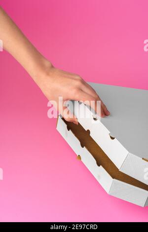 Weibliche Hand Öffnung Pizza Lieferbox auf rosa Hintergrund Stockfoto